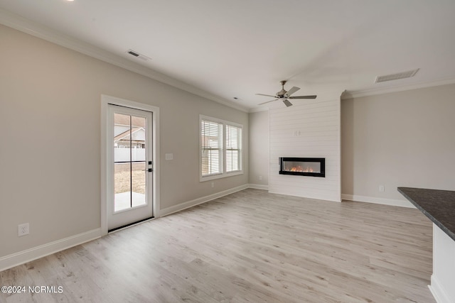 unfurnished living room with light wood-type flooring, a large fireplace, ceiling fan, and crown molding