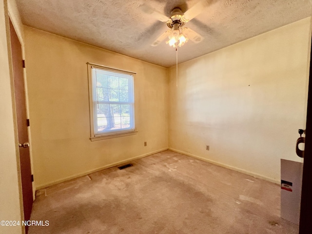 spare room featuring carpet floors, visible vents, a textured ceiling, and baseboards