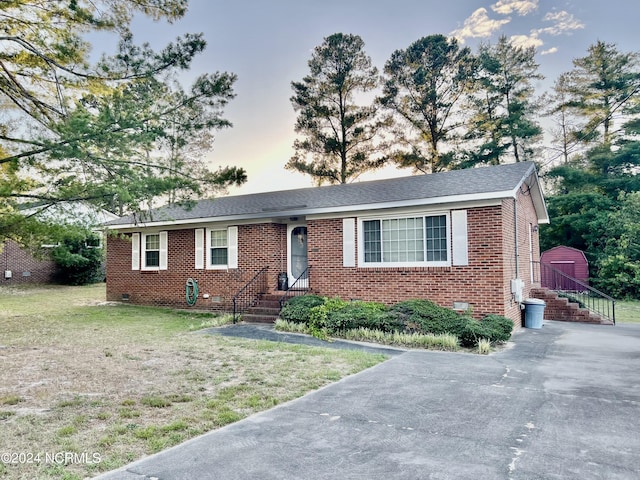 ranch-style house featuring crawl space, a shingled roof, a front lawn, and brick siding