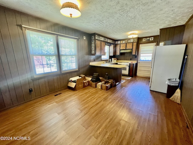 kitchen with a peninsula, dark wood-style flooring, visible vents, light countertops, and freestanding refrigerator