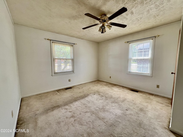 carpeted spare room with a healthy amount of sunlight, visible vents, and a textured ceiling