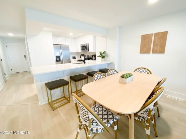 dining area with light wood-type flooring and sink