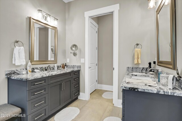 bathroom with two vanities, a sink, and baseboards