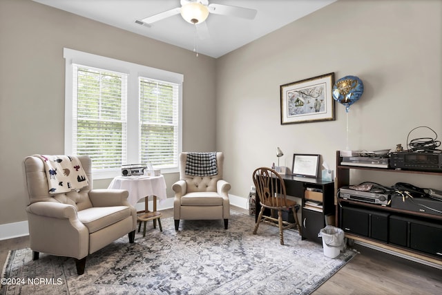 sitting room with a ceiling fan, wood finished floors, visible vents, and baseboards