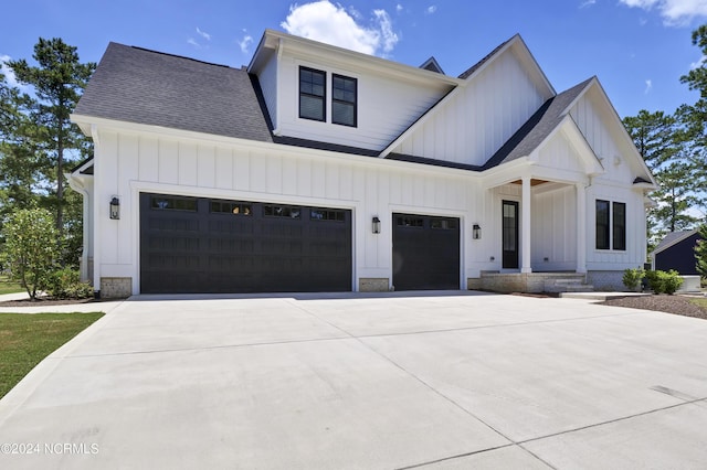 modern farmhouse style home with driveway, an attached garage, board and batten siding, and roof with shingles