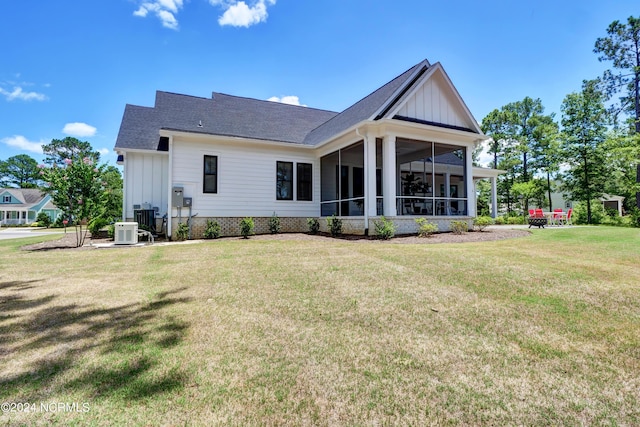 back of property with a sunroom, board and batten siding, cooling unit, and a lawn