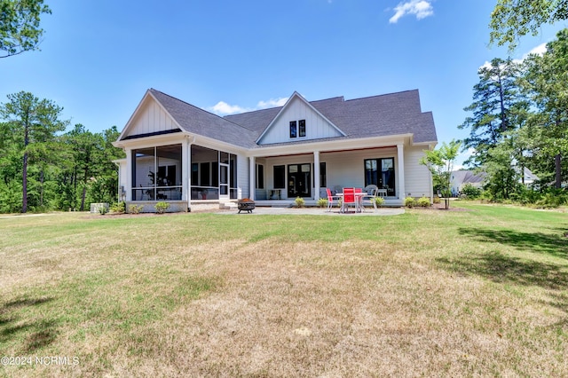 rear view of property with a yard, board and batten siding, a patio area, and a sunroom