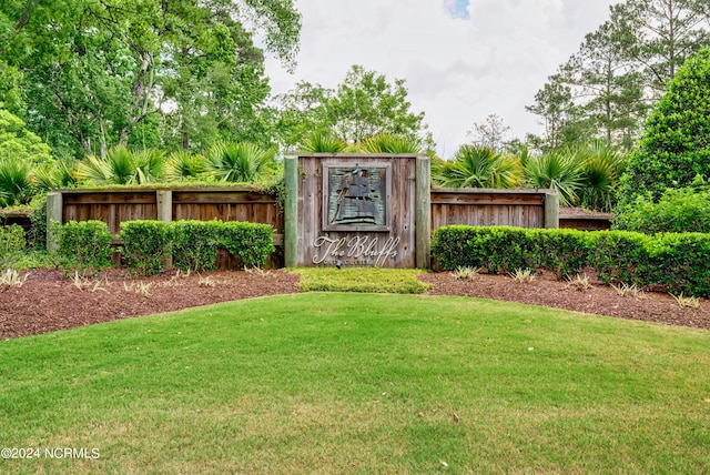 community / neighborhood sign featuring a yard and fence