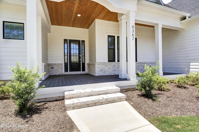 doorway to property with covered porch and brick siding