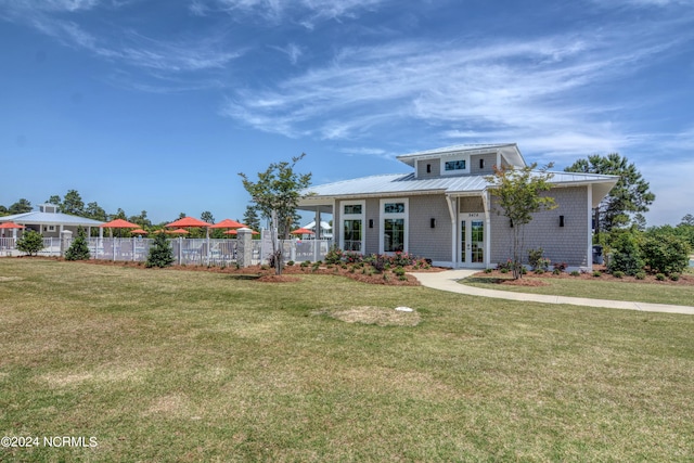 view of front of home with metal roof, french doors, a front lawn, and fence