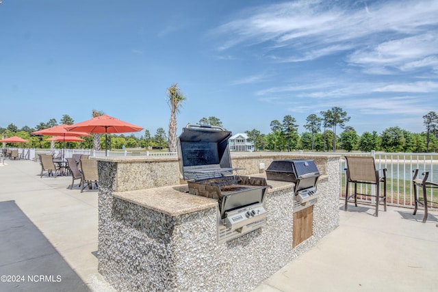 view of patio with an outdoor kitchen, outdoor dry bar, fence, and grilling area