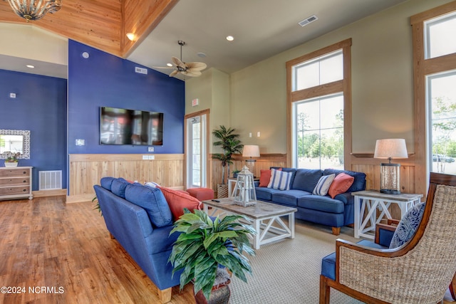 living area with a wealth of natural light, a wainscoted wall, visible vents, and a towering ceiling