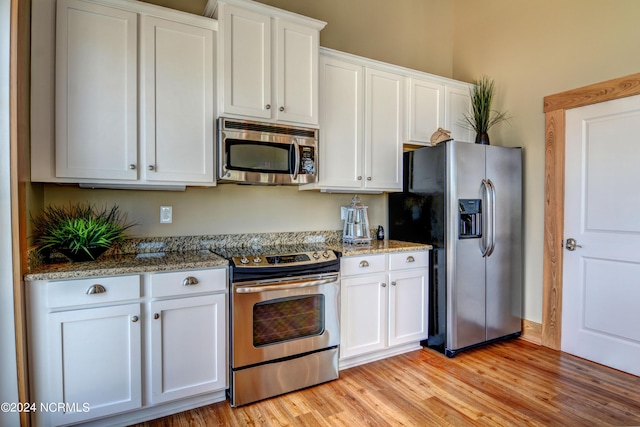 kitchen featuring stainless steel appliances, light wood-style flooring, and white cabinets