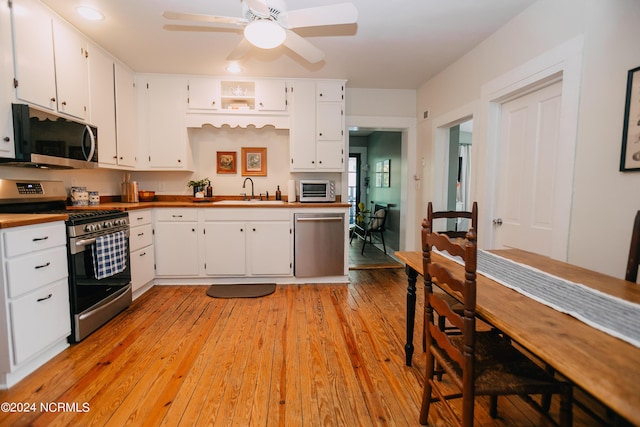 kitchen featuring appliances with stainless steel finishes, ceiling fan, sink, light hardwood / wood-style floors, and white cabinetry