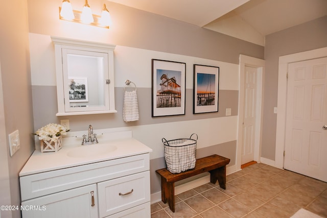 bathroom with tile patterned flooring, vanity, and vaulted ceiling