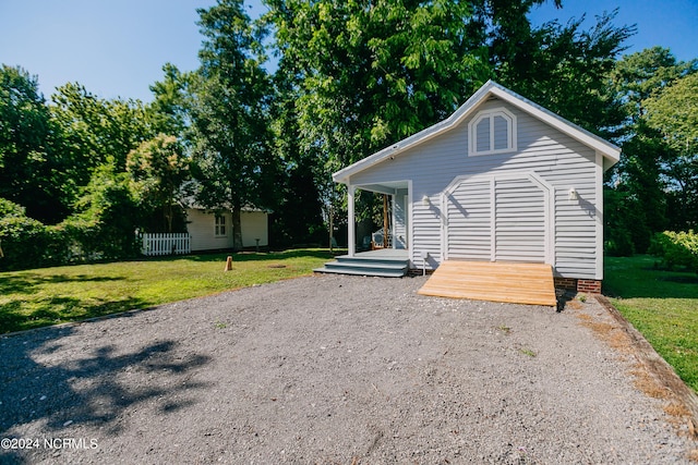 view of front of house with a front lawn, covered porch, and an outdoor structure