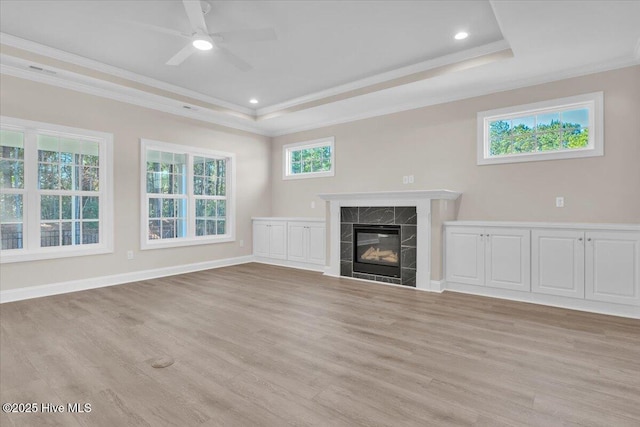 unfurnished living room featuring light wood-style flooring, ornamental molding, a raised ceiling, and a high end fireplace