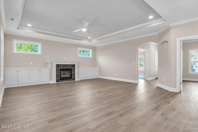 unfurnished living room with arched walkways, a tray ceiling, and a fireplace