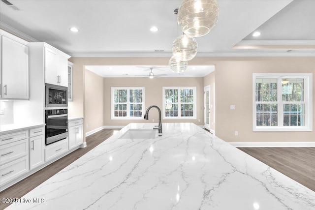 kitchen featuring wall oven, visible vents, light stone counters, stainless steel microwave, and a sink