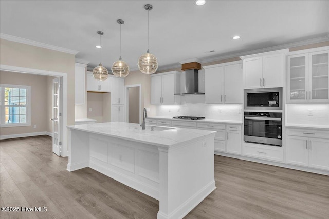 kitchen with wall chimney range hood, backsplash, stainless steel appliances, and a sink