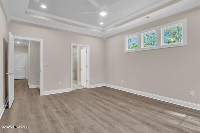 unfurnished bedroom with baseboards, a tray ceiling, and wood finished floors