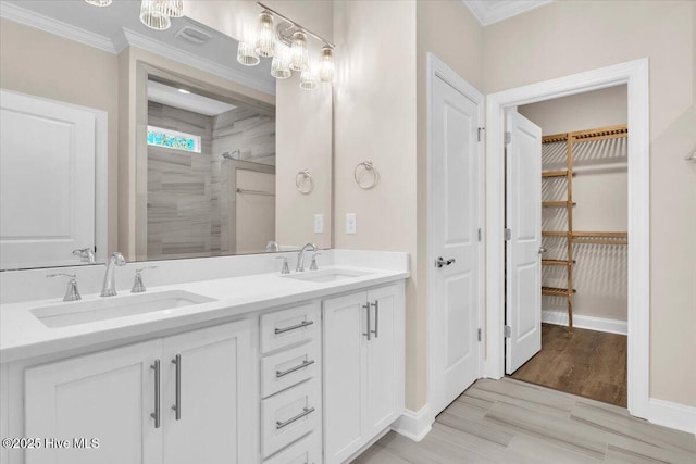 full bathroom featuring double vanity, crown molding, a walk in closet, and a sink