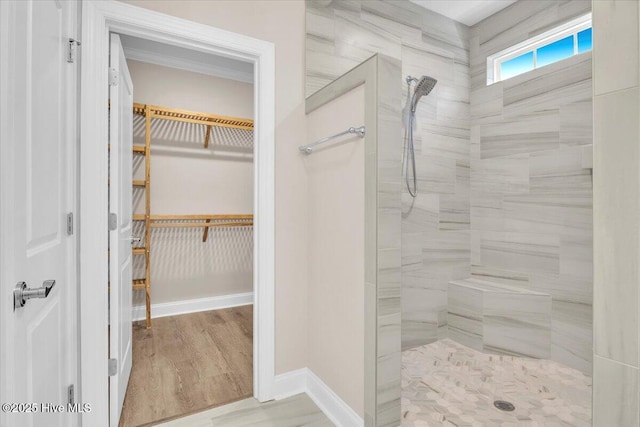 full bathroom featuring tiled shower, a spacious closet, baseboards, and wood finished floors