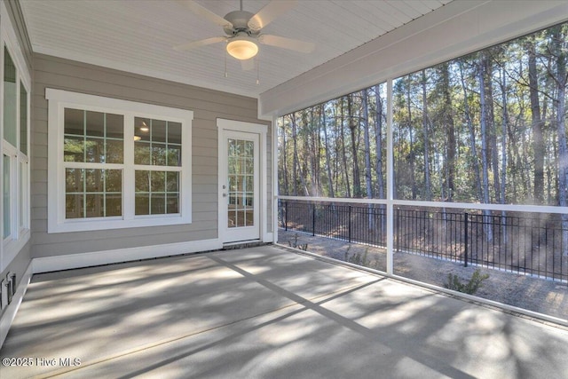 unfurnished sunroom featuring a ceiling fan and a wealth of natural light