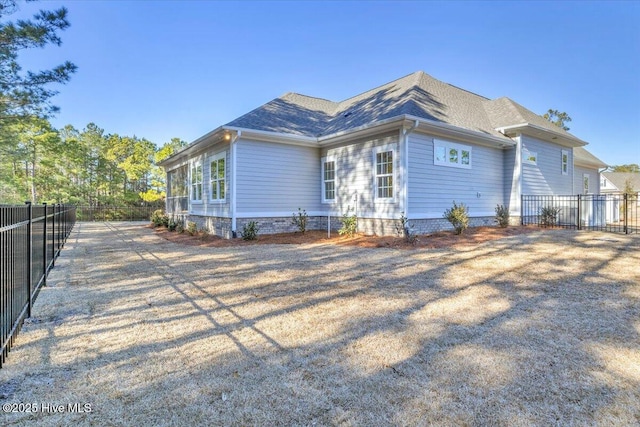 view of side of home featuring a shingled roof and fence