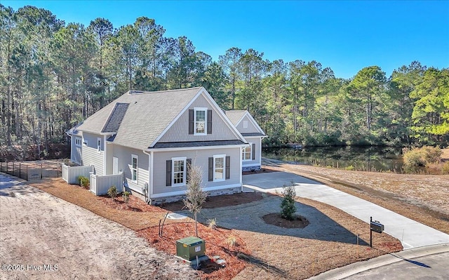 view of front of house with a shingled roof, driveway, and a view of trees