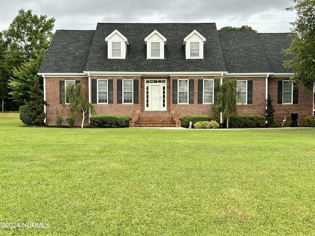 new england style home featuring brick siding, a front yard, roof with shingles, and entry steps