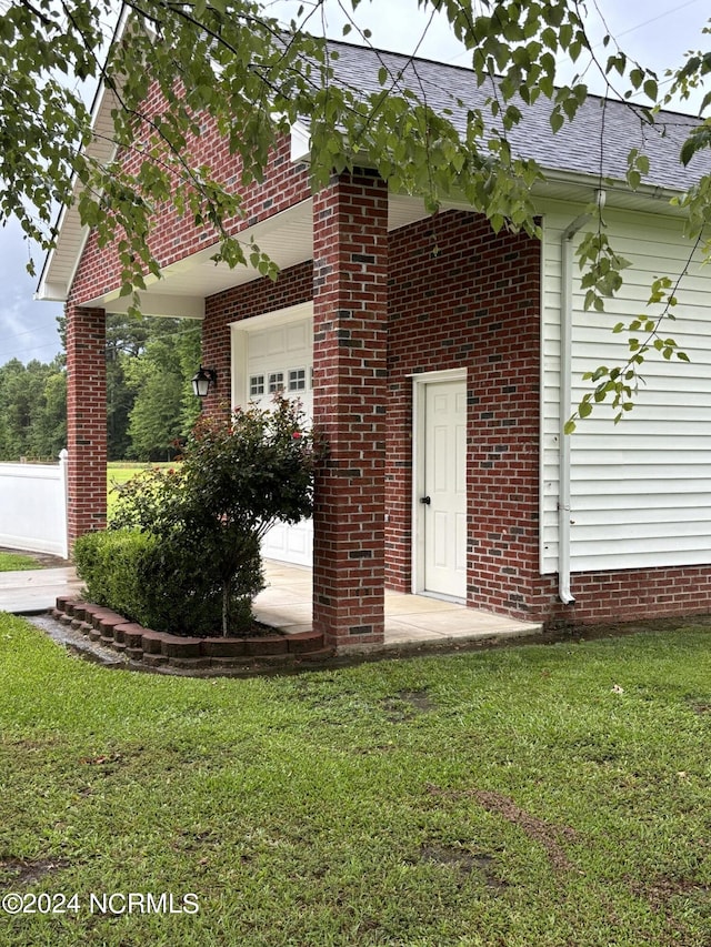 exterior space featuring brick siding, a lawn, roof with shingles, and an attached garage