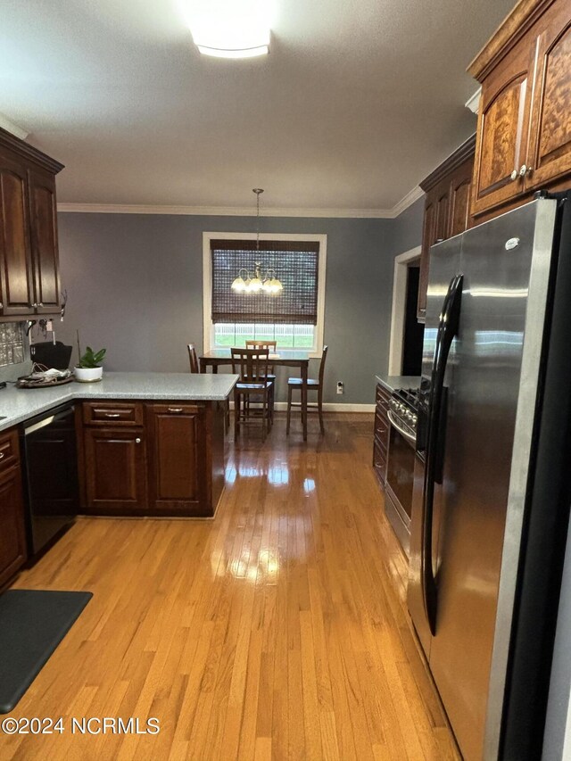 kitchen featuring light hardwood / wood-style flooring, an inviting chandelier, hanging light fixtures, appliances with stainless steel finishes, and ornamental molding