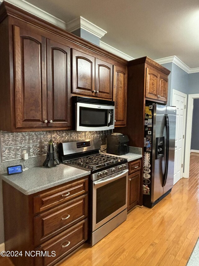 kitchen with stainless steel appliances, crown molding, light wood-type flooring, dark brown cabinetry, and backsplash