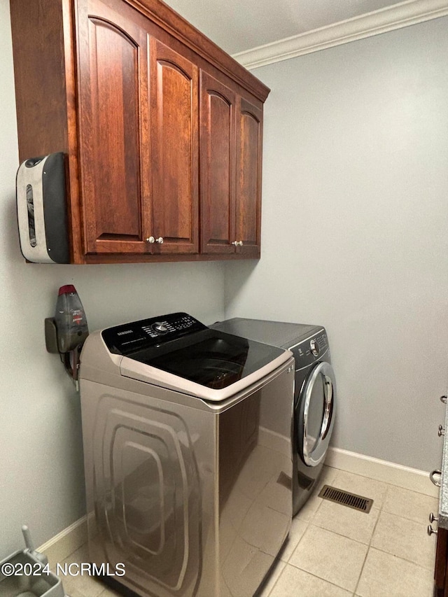 laundry room featuring cabinets, crown molding, independent washer and dryer, and light tile patterned floors