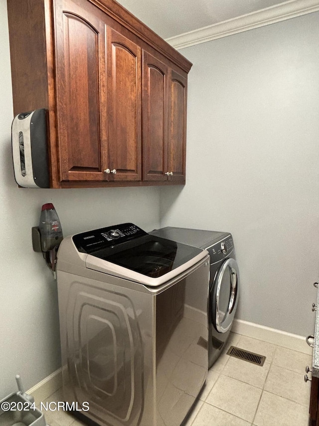 laundry area with washing machine and dryer, crown molding, visible vents, baseboards, and cabinet space