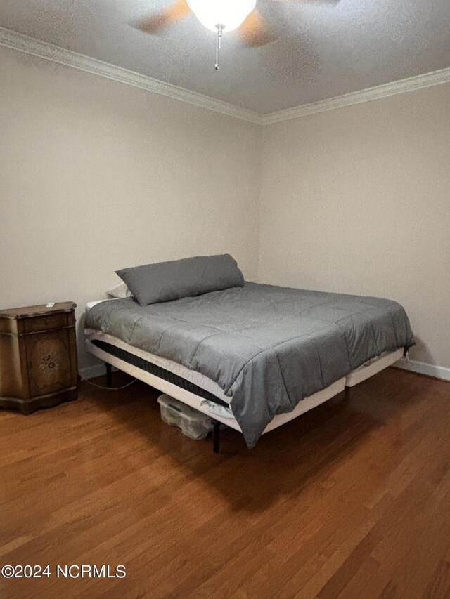 bedroom with hardwood / wood-style flooring, a textured ceiling, ornamental molding, and ceiling fan