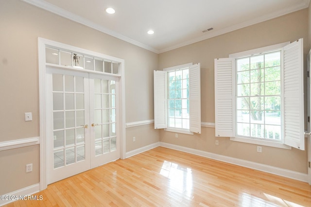 empty room featuring french doors, light hardwood / wood-style flooring, plenty of natural light, and crown molding