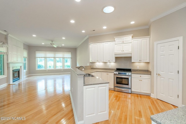 kitchen featuring sink, kitchen peninsula, ceiling fan, stainless steel range, and white cabinetry