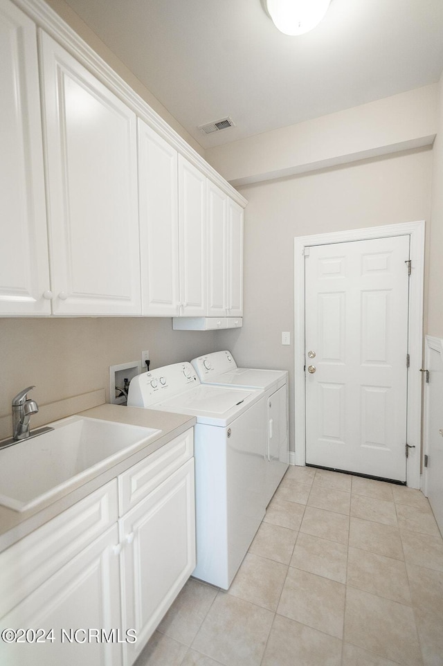 laundry room featuring cabinets, light tile patterned floors, washer and dryer, and sink