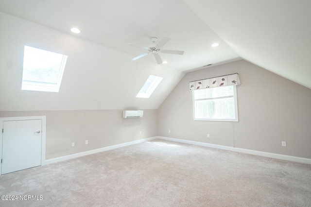 bonus room featuring an AC wall unit, ceiling fan, vaulted ceiling with skylight, and light carpet