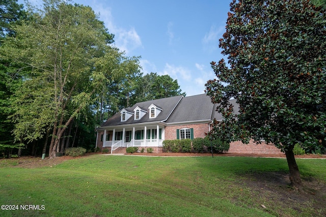 cape cod home with covered porch and a front lawn