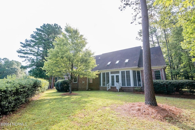 rear view of property with a sunroom and a yard