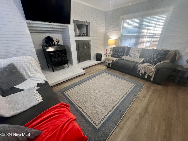 living room featuring hardwood / wood-style floors, ornamental molding, and brick wall