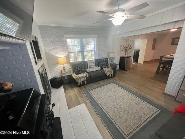 living room featuring ornamental molding, hardwood / wood-style floors, and brick wall