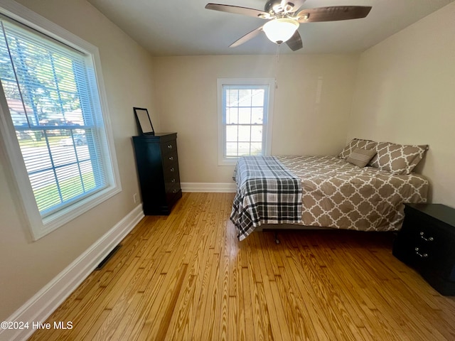 bedroom featuring light wood-type flooring, multiple windows, and ceiling fan