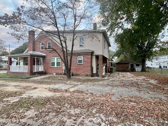 rear view of property featuring covered porch and an outbuilding