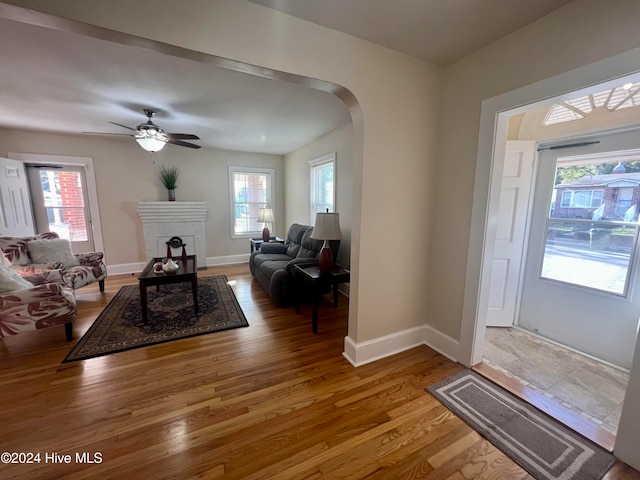 entrance foyer featuring a fireplace, wood-type flooring, a healthy amount of sunlight, and ceiling fan