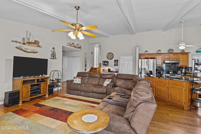 living room with beam ceiling, light wood-type flooring, and ceiling fan