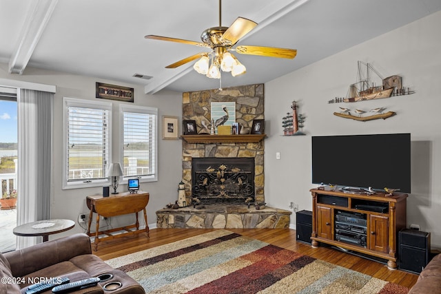 living room featuring hardwood / wood-style floors, beam ceiling, a fireplace, and ceiling fan